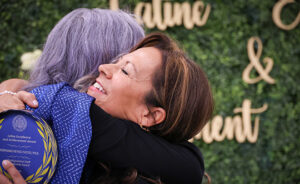 Vice Provost Reyes-Tuccio embraced after she receives award